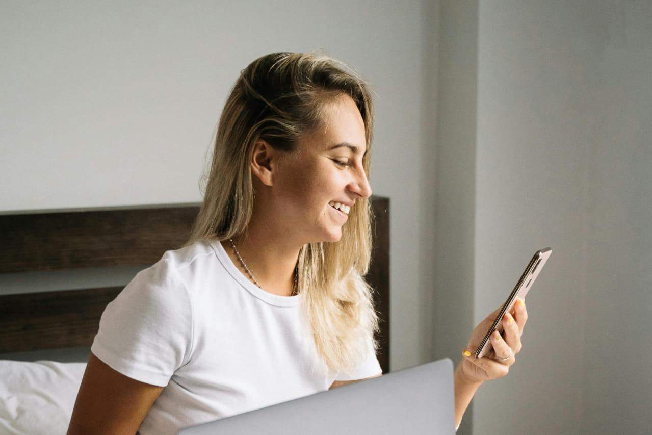 A smiling woman checks the return status of her order on a smartphone