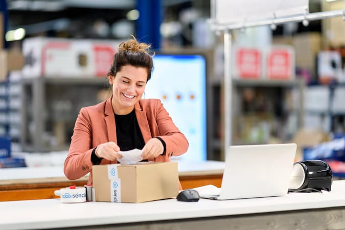 woman sticks label on package in warehouse